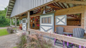 A rustic building with a covered porch, wooden benches, and Adirondack chairs. - Farmhouse Hideaway w/ Covered Patio in Kissimmee (Kissimmee)