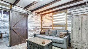 A rustic interior with a wooden door, a sofa with cushions, a coffee table, and a wooden cabinet. - Farmhouse Hideaway w/ Covered Patio in Kissimmee (Kissimmee)