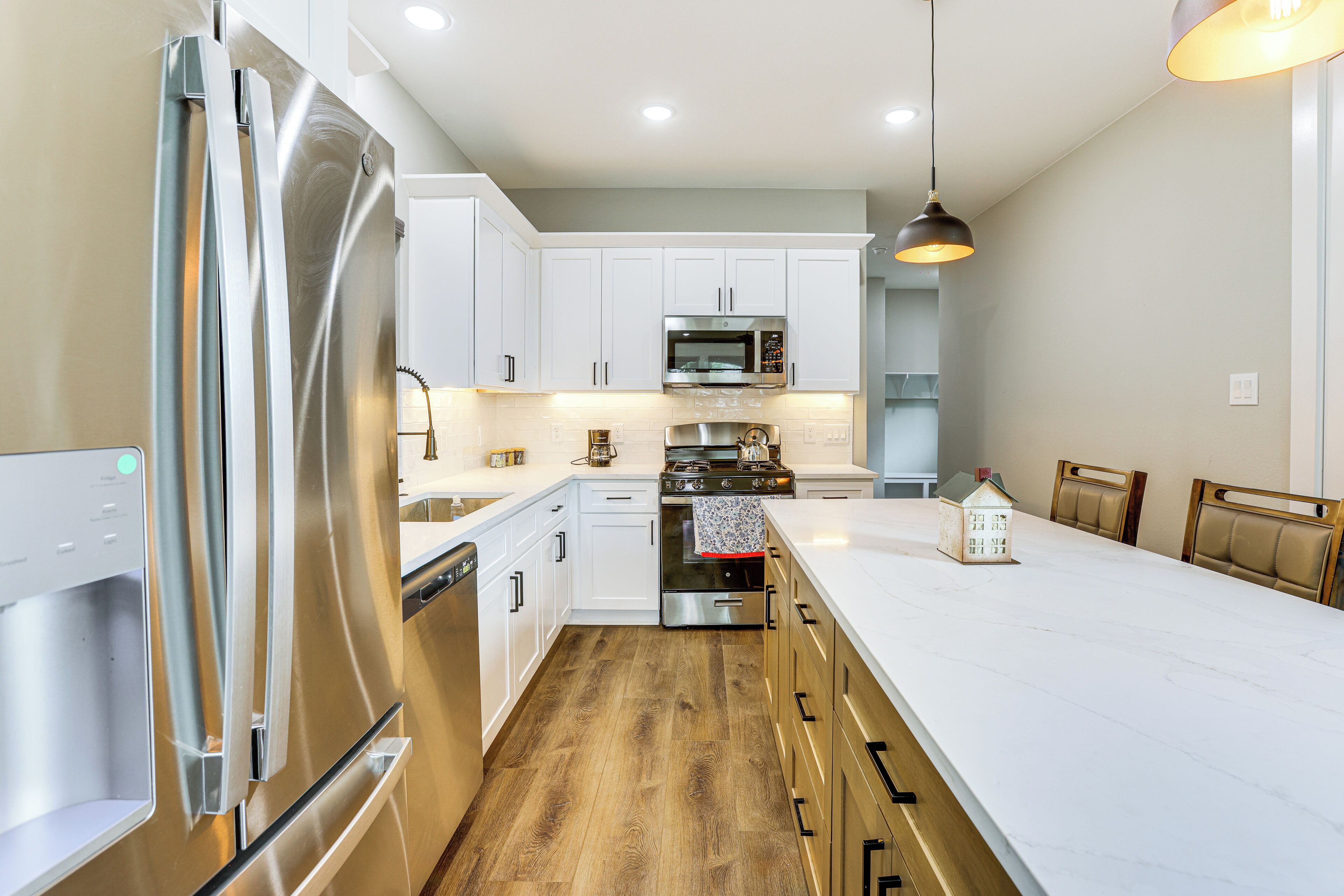 Una cocina moderna con electrodomésticos de acero inoxidable, muebles blancos y suelo de madera.