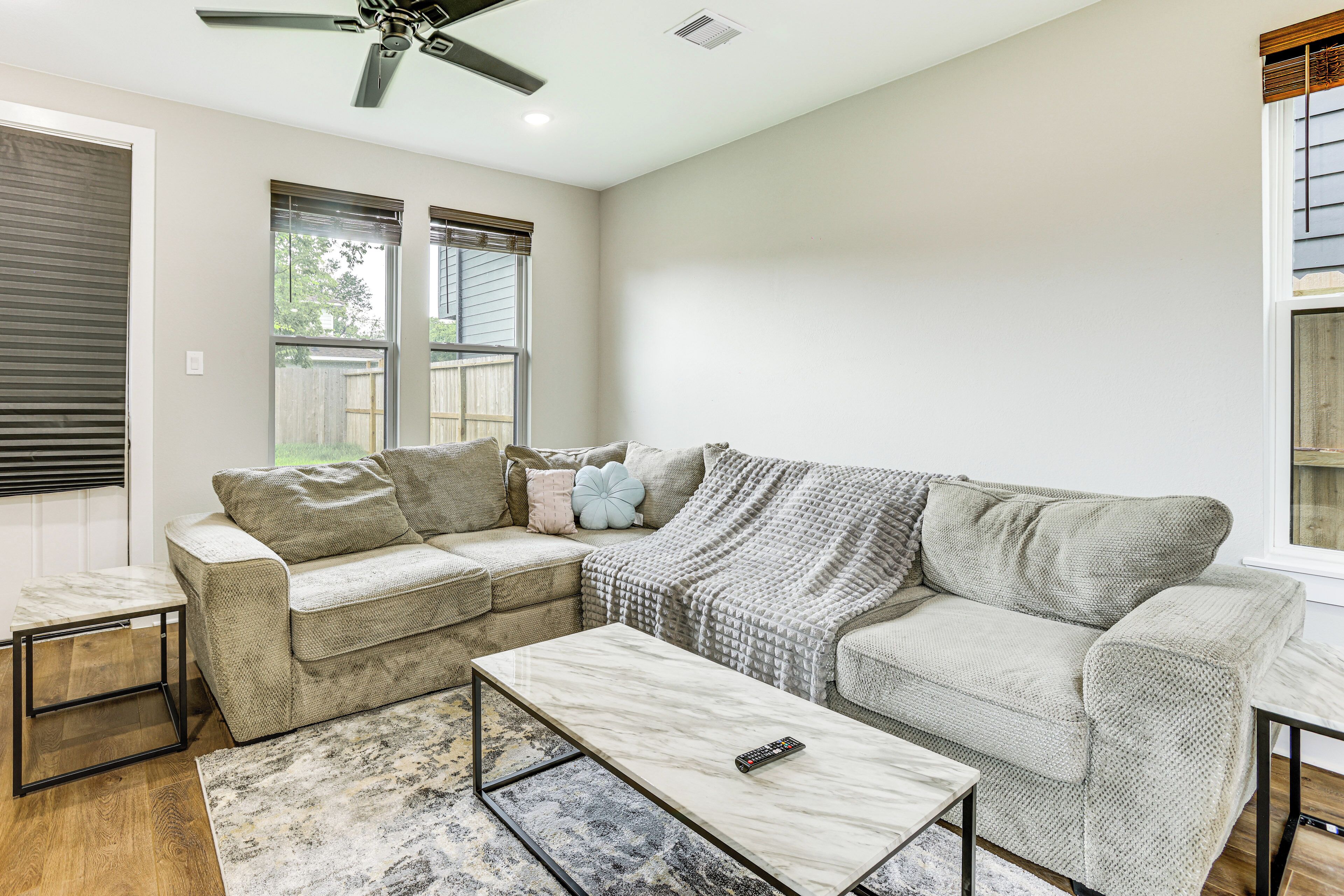 A living room with a beige sofa, a coffee table, and a ceiling fan.