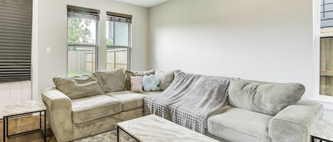 A living room with a beige sofa, a coffee table, and a ceiling fan.