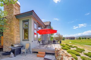 A house with a stone chimney, a patio with outdoor furniture, and a red umbrella. - Grand Elk Golf Club On-site: Mtn-view Home w/ Deck (Granby)
