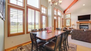 A spacious dining area with a wooden table and chairs, large windows, and a fireplace. - Grand Elk Golf Club On-site: Mtn-view Home w/ Deck (Granby)