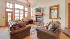 A spacious living room with leather sofas, a stone fireplace, and large windows. - Grand Elk Golf Club On-site: Mtn-view Home w/ Deck (Granby)