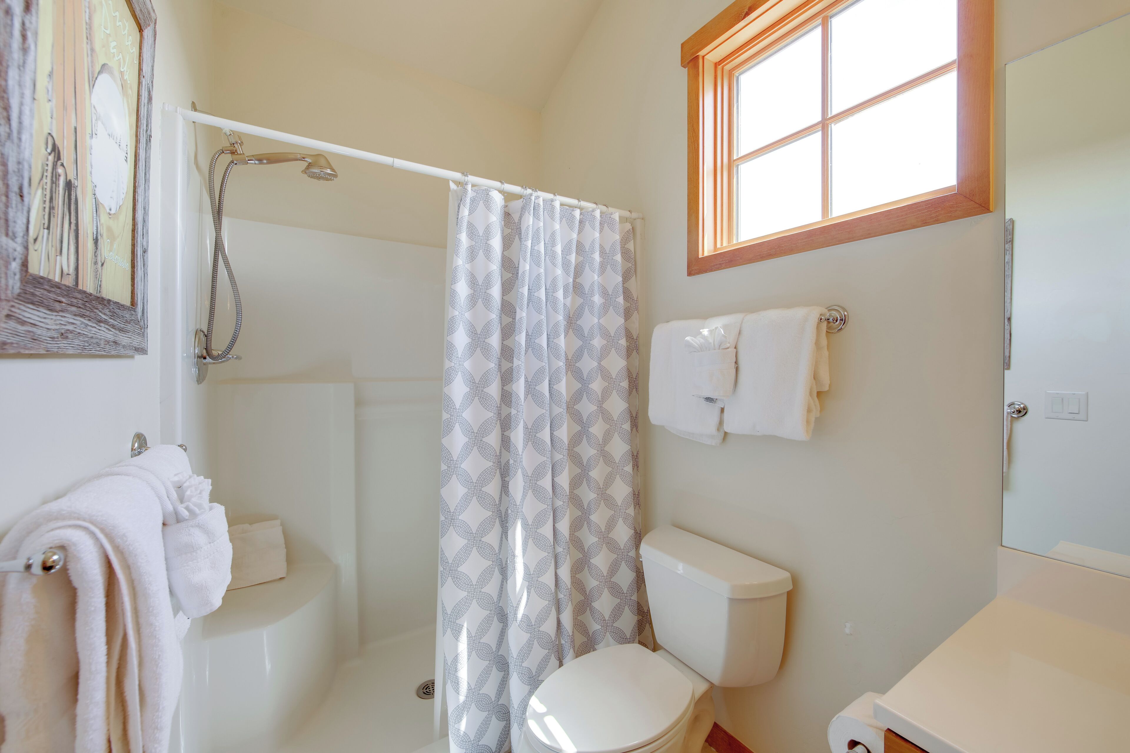 Une salle de bain avec une douche, des toilettes et une fenêtre.