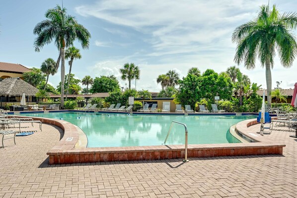Una piscina con sillas de descanso y palmeras.