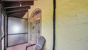 A wooden chair in a corridor with a textured wall and a door with shutters. - Everglades Escape w/ Heated Pool & Marina Access! (Naples)