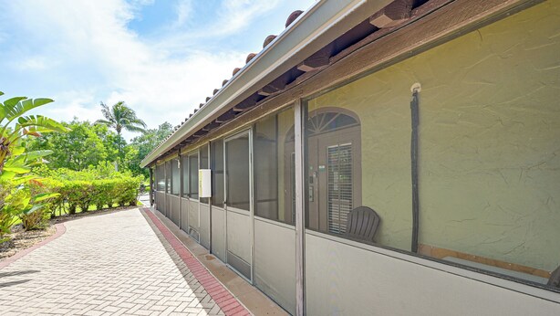 A covered outdoor area with a brick pathway, large windows, and a view of greenery. - Everglades Escape w/ Heated Pool & Marina Access! (Naples)