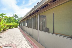 A covered outdoor area with a brick pathway, large windows, and a view of greenery. - Everglades Escape w/ Heated Pool & Marina Access! (Naples)