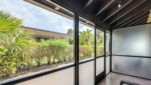 A modern room with large windows, a concrete floor, and a view of a garden with various plants. - Everglades Escape w/ Heated Pool & Marina Access! (Naples)