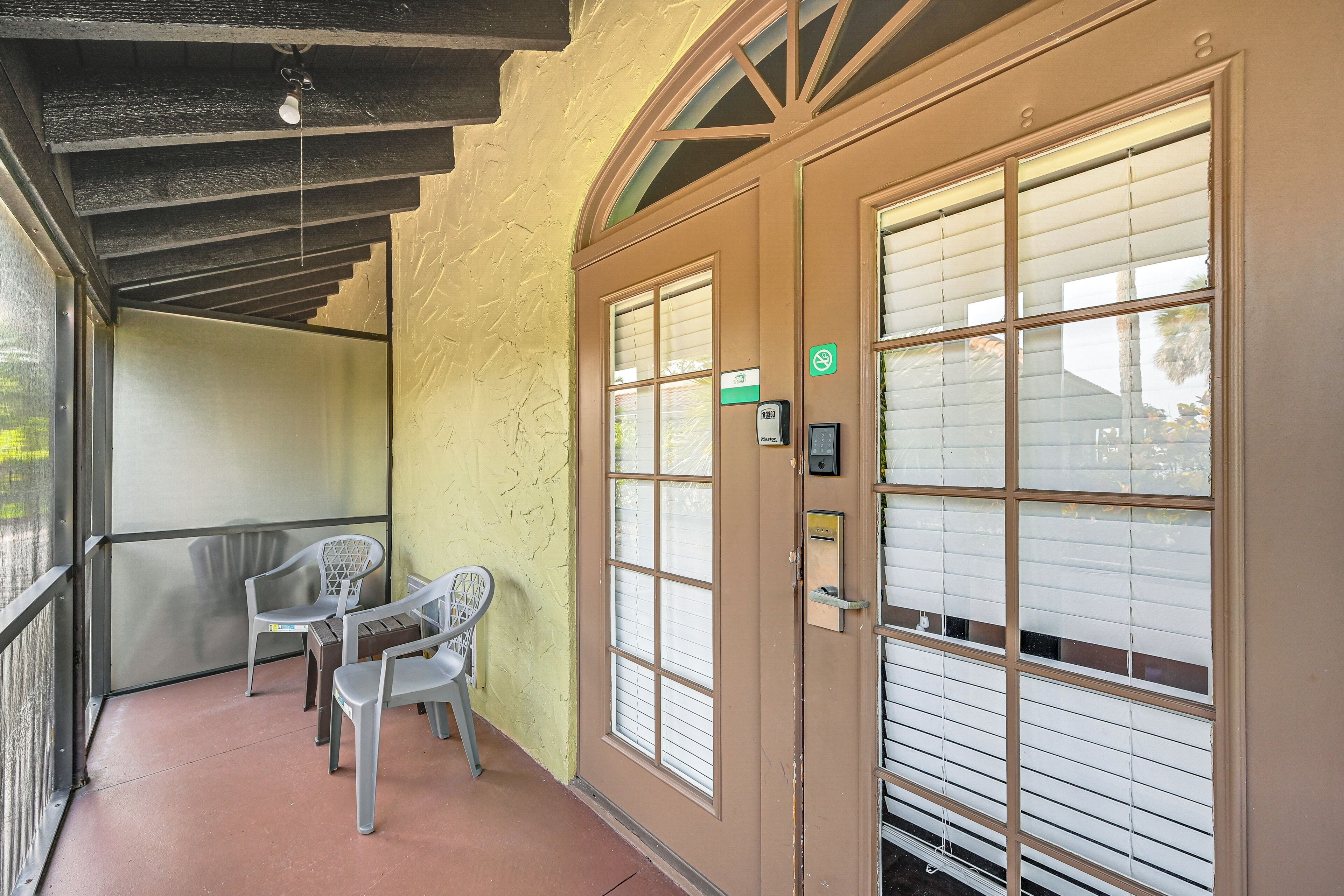 A hotel room with a balcony, a door with a keypad, and a window with blinds.