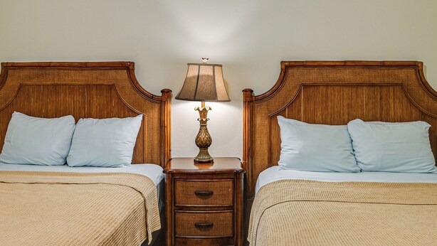 A double room with two wooden headboards, a nightstand with a lamp, and a bed with a beige blanket. - Bring Your Boat: Condo w/ Pool in Naples! (Naples)