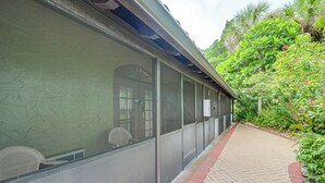 A building with large windows, a covered walkway, and a garden area with various plants and trees. - Bring Your Boat: Condo w/ Pool in Naples! (Naples)