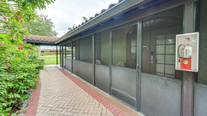 A covered outdoor area with a tiled roof, a fire extinguisher mounted on the wall, and a brick pathway. - Bring Your Boat: Condo w/ Pool in Naples! (Naples)