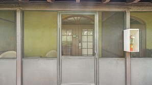 Ein Zimmer mit großem Fenster, einer Tür und einem kleinen Kühlschrank.