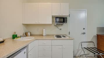 A kitchen with white cabinets, a microwave, a sink, and a stove.