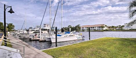 A marina with boats docked, a grassy area, and a building in the background.