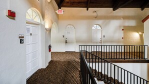 A hallway with white walls, arched doorways, and a patterned carpet. - Exclusive 10K Islands Access: Hotel-style Studio (Naples)