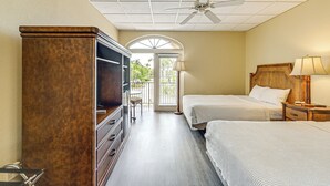 A hotel room with two beds, a TV, a wooden dresser, and a ceiling fan. - Marina, Heated Pool & Game Room: Naples Condo! (Naples)