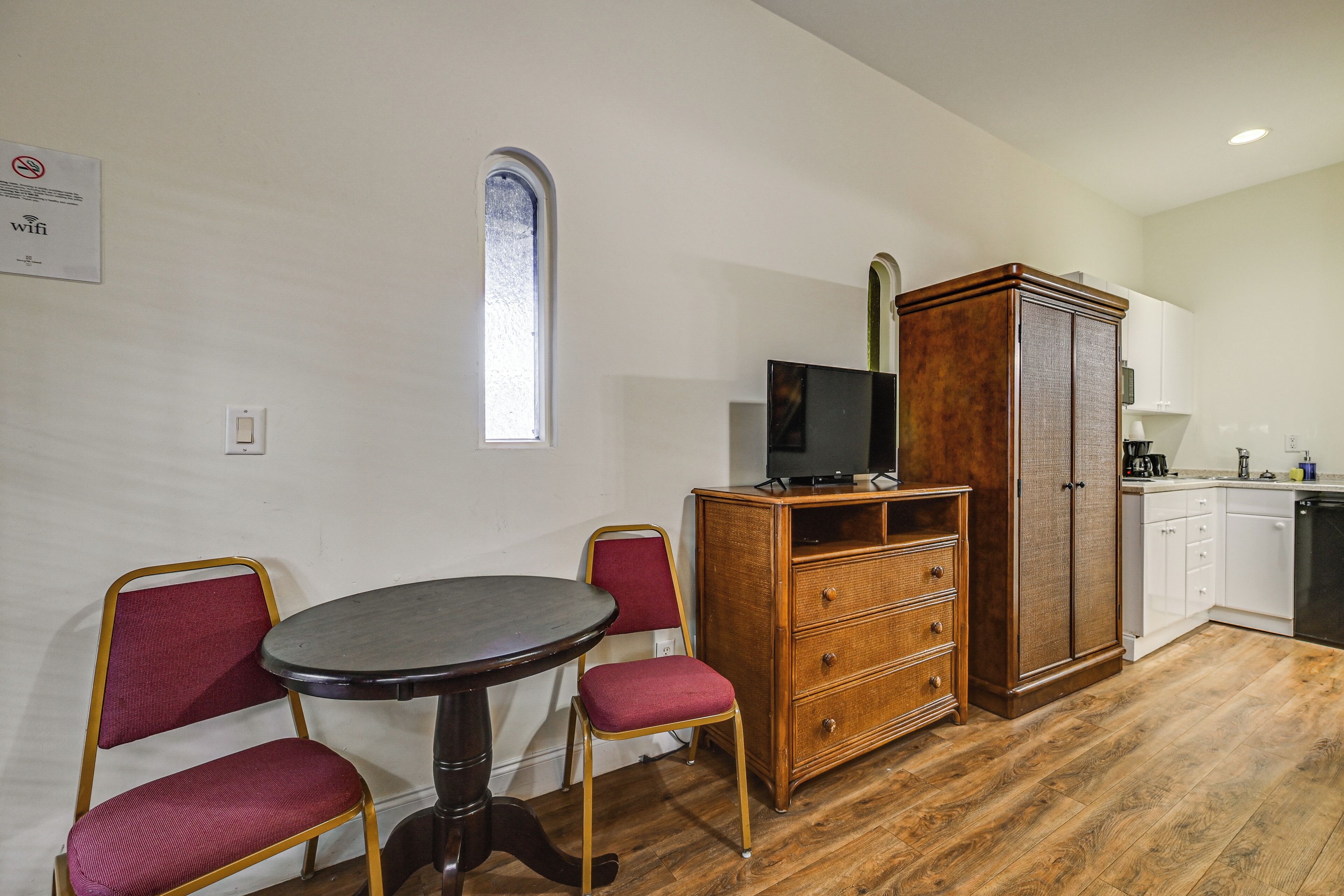 Una cocina compacta con zona de comedor, que incluye una mesa redonda, dos sillas, un armario y un televisor.