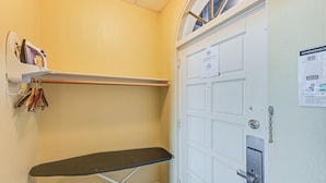 A corner of a room with a white door, a small ironing board, and a shelf with ironing supplies. - Everglades Studio: Heated Pool Access, 15 Mi to NP (Naples)