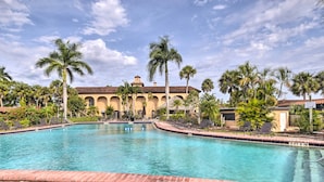 A swimming pool with a brick border, palm trees, and a building with a tiled roof in the background. - Everglades Studio: Heated Pool Access, 15 Mi to NP (Naples)