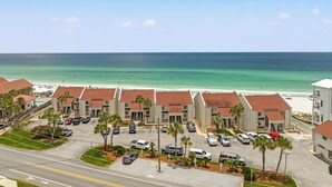 A beachfront hotel with multiple buildings, a parking lot, and a view of the ocean. - Latitude 29 Condominiums #18 | Gulf Front + Amenities (Panama City Beach)