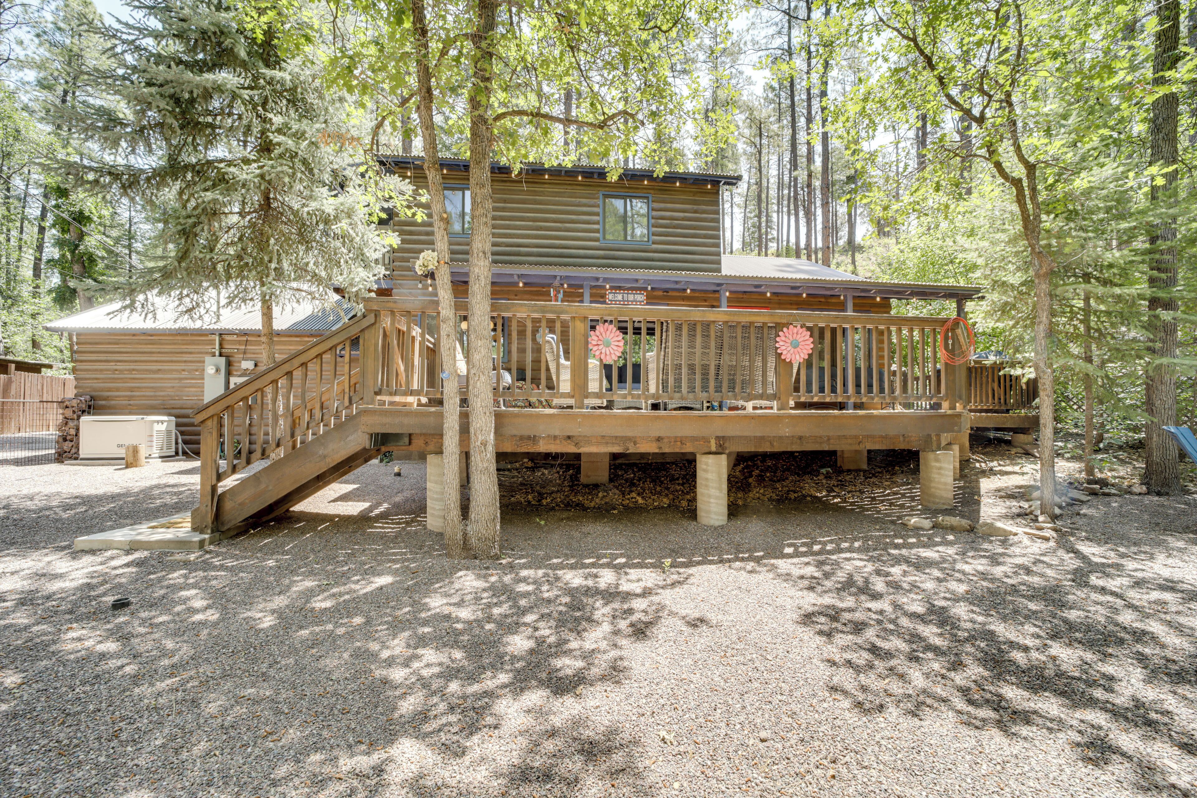 Eine Holzhütte mit einer Holzterrasse, einer Treppe und Blick auf den umliegenden Wald.