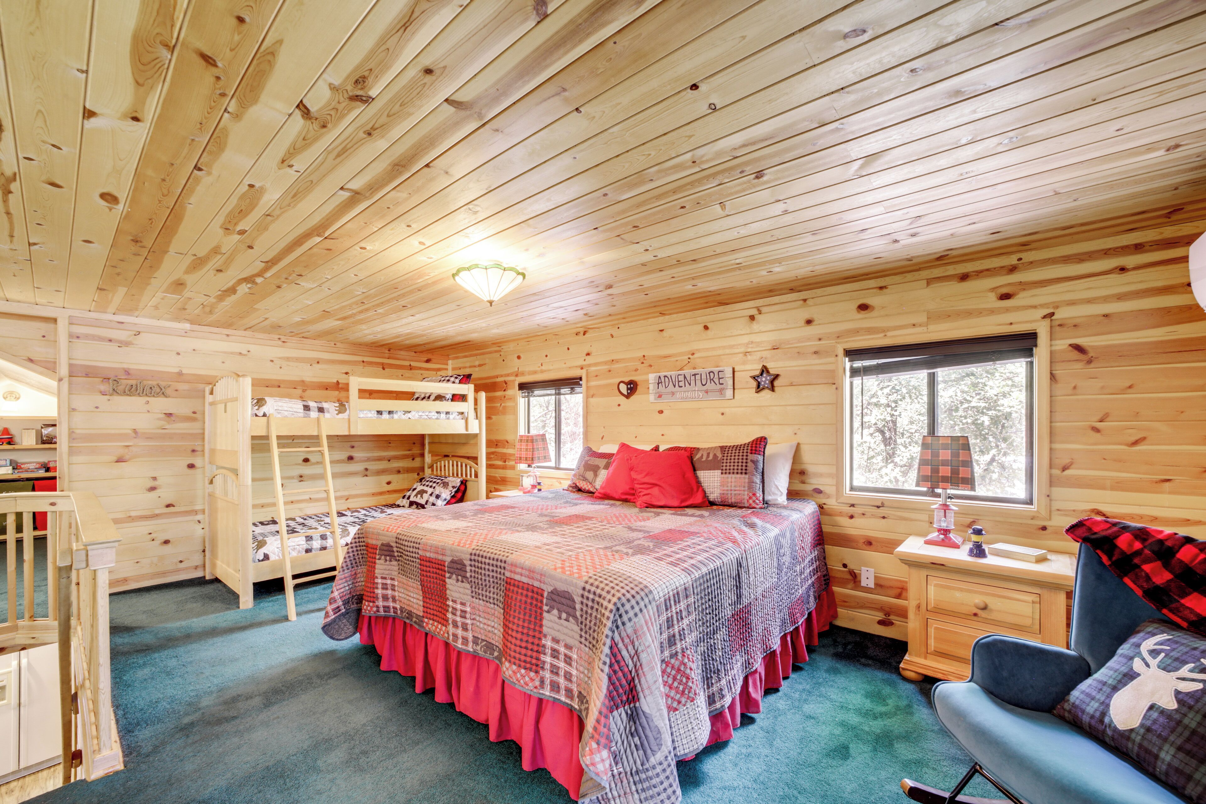 A wooden cabin bedroom with bunk beds, a desk, and a chair.