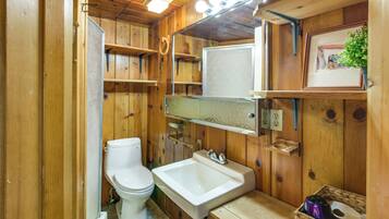 Une salle de bain en bois avec des toilettes, un lavabo et des étagères.
