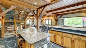 A spacious kitchen with wooden beams, a stone floor, and a large island with a built-in oven. - Riverfront Hudson Valley Gem w/ Beach Access! (Athens)