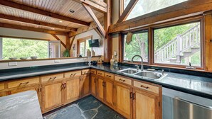 A kitchen with wooden cabinets, a granite countertop, a large window with a view of a wooden deck, and a stone backsplash. - Riverfront Hudson Valley Gem w/ Beach Access! (Athens)
