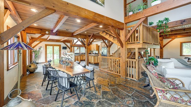 A spacious interior with a stone floor, wooden beams, a dining area with chairs, a staircase, and a living area with a sofa. - Riverfront Hudson Valley Gem w/ Beach Access! (Athens)