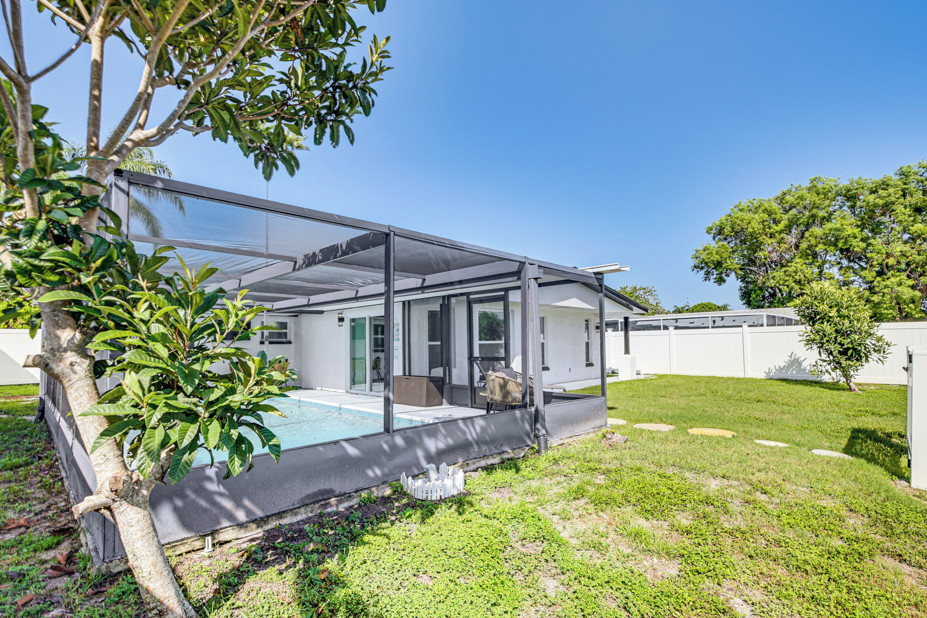 A modern house with a covered outdoor area, a swimming pool, and a well-maintained lawn.