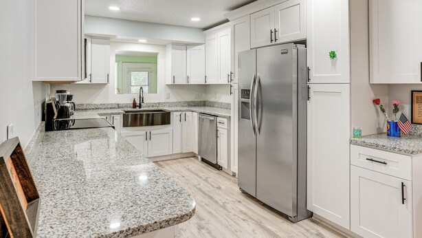 A modern kitchen with white cabinets, granite countertops, stainless steel appliances, and a green window. - Group Getaway w/ Deck & Yard in Lakeland! (Lakeland)