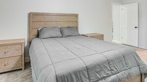 A bedroom with a wooden headboard, a grey bedspread, two bedside tables, and a white door. - Group Getaway w/ Deck & Yard in Lakeland! (Lakeland)