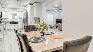 A modern kitchen with white cabinets, a marble countertop, and a dining area with a table and chairs. - Group Getaway w/ Deck & Yard in Lakeland! (Lakeland)