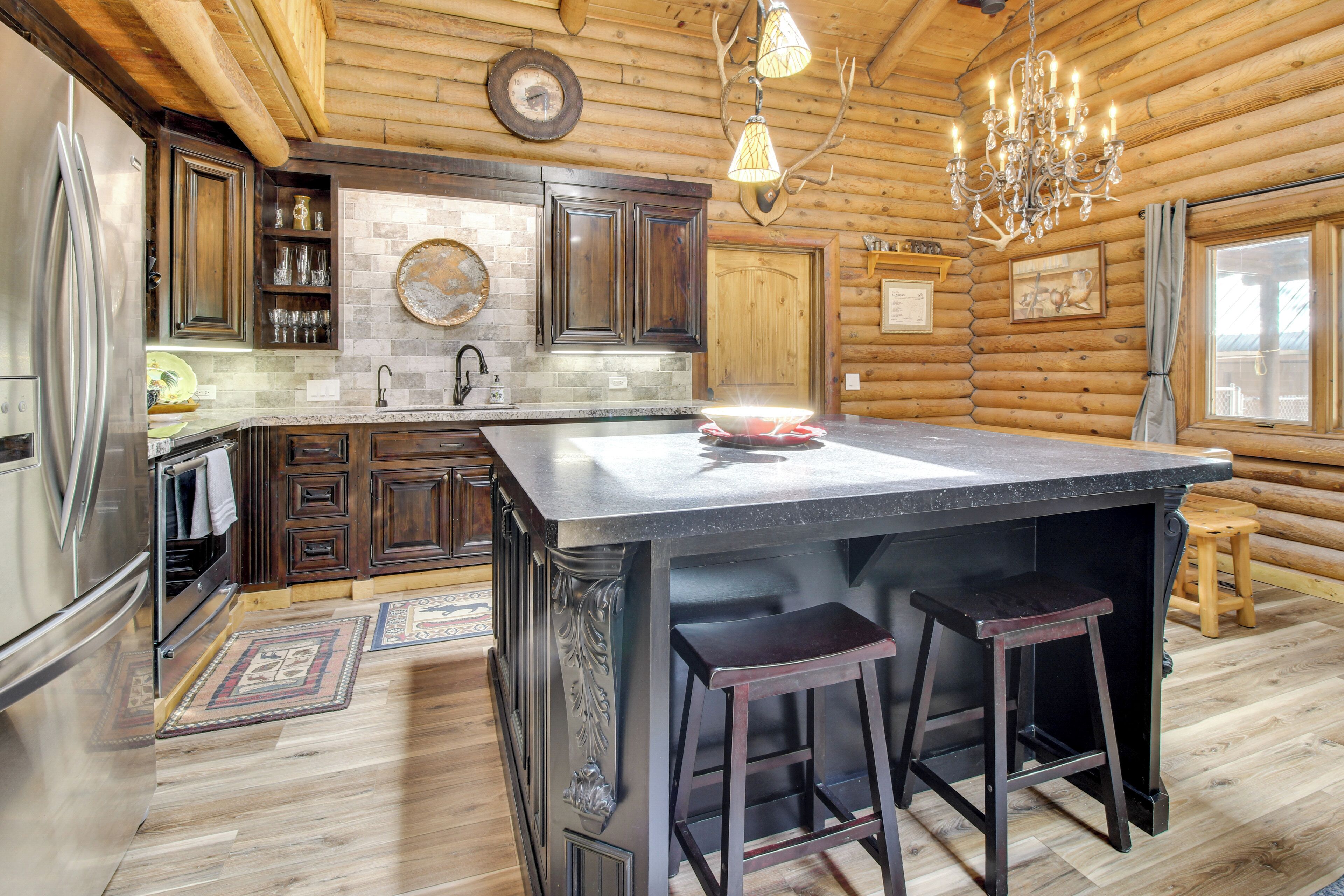 Cocina de cabaña de madera con una isla grande, armarios de madera oscura, un refrigerador de acero inoxidable y una araña.