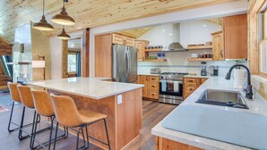 A spacious kitchen with wooden cabinets, a large island with bar stools, stainless steel appliances, and pendant lighting. - 3 Mi to Resort: Year-round Angel Fire Getaway! (Angel Fire)