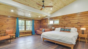 A spacious bedroom with a wooden ceiling, a large bed, a nightstand, and a window with curtains. - 3 Mi to Resort: Year-round Angel Fire Getaway! (Angel Fire)