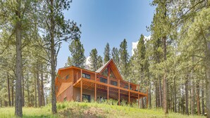 A wooden cabin with a large deck, surrounded by tall pine trees. - 3 Mi to Resort: Year-round Angel Fire Getaway! (Angel Fire)