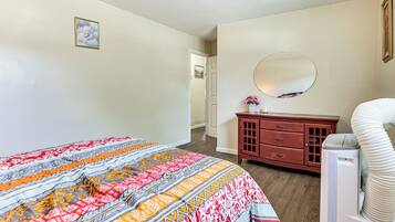 A bedroom with a large bed, a dresser, a mirror, and a heater.