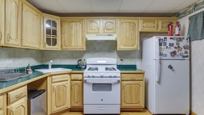 Una cocina con armarios de madera, una estufa blanca y un refrigerador blanco.