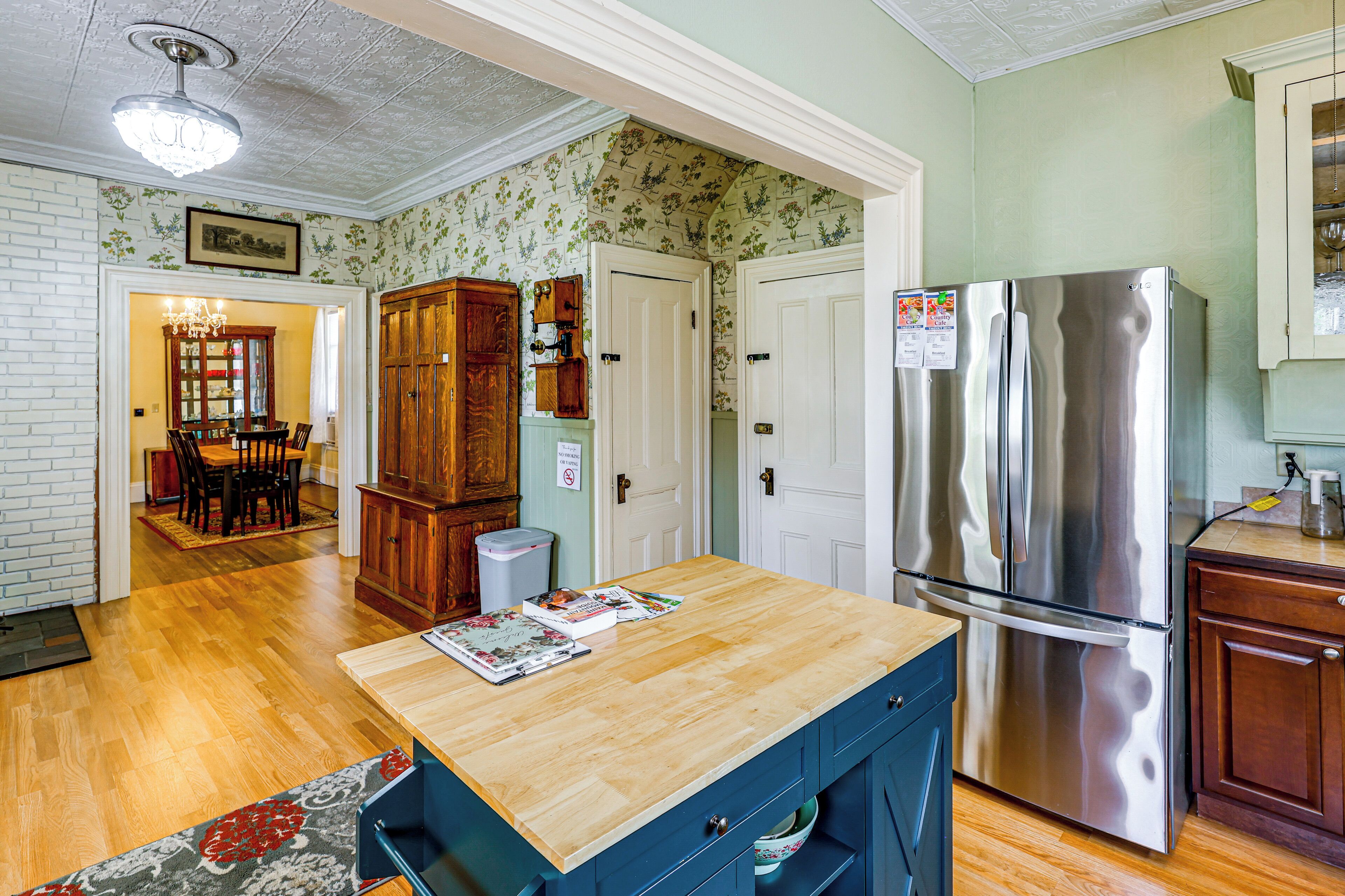 A kitchen with wooden cabinets, a stainless steel refrigerator, and a wooden dining table with chairs.
