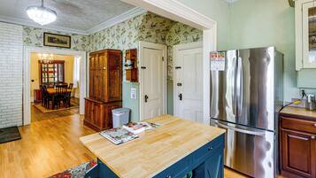 A kitchen with wooden cabinets, a stainless steel refrigerator, and a wooden dining table with chairs.