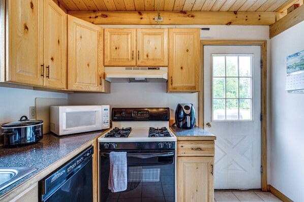 A kitchen with wooden cabinets, a microwave, a stove, and a dishwasher.