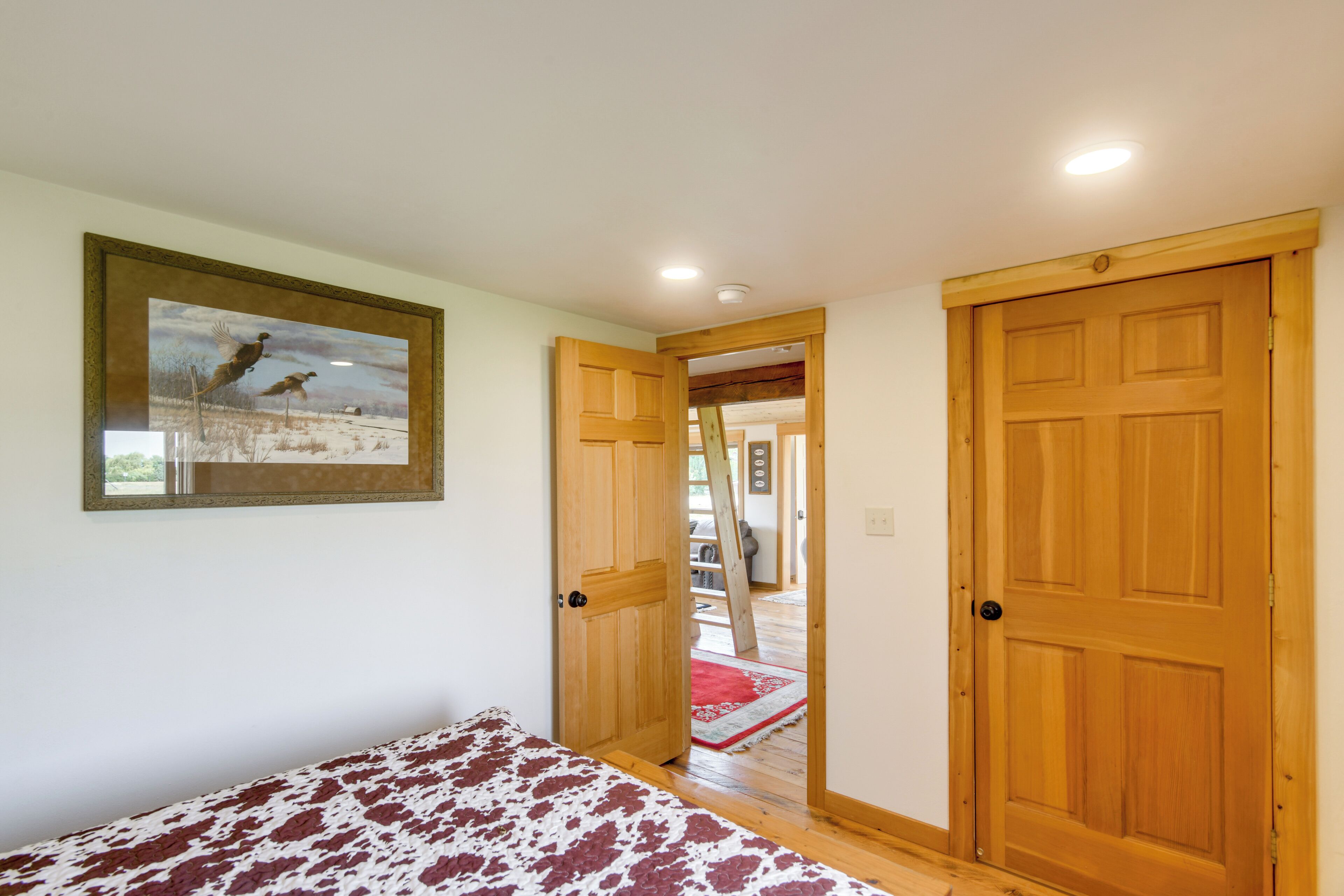 A bedroom with a bed, wooden doors, and a painting on the wall.