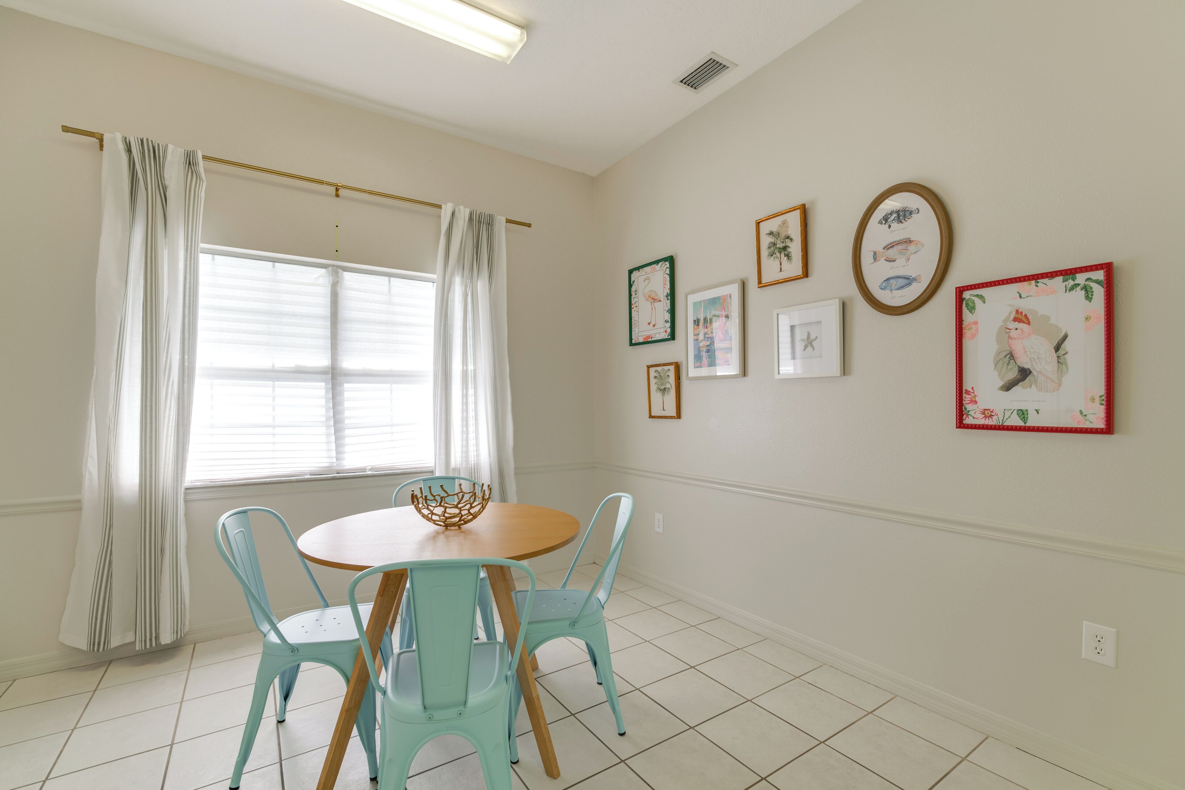 A dining area with a round table, four light blue chairs, and a decorative bowl.