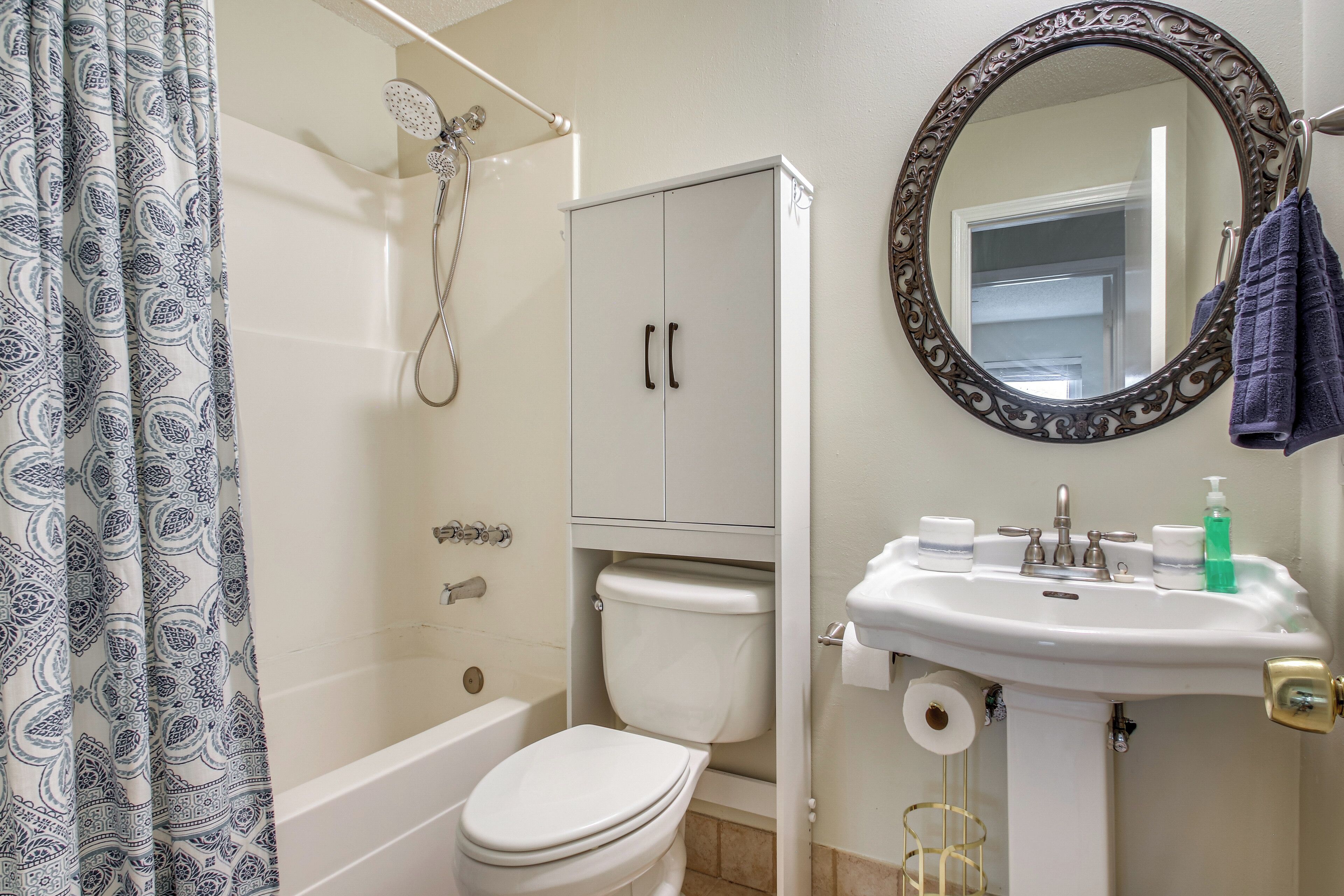 A bathroom with a toilet, shower, and sink.