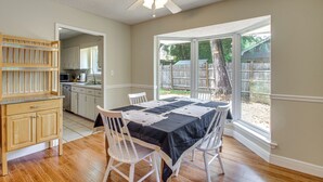 A dining area with a table set for four, a ceiling fan, and a view of a backyard through large windows. - Shop, Dine & Visit Uwf: Pensacola Home w/ Yard! (Pensacola)